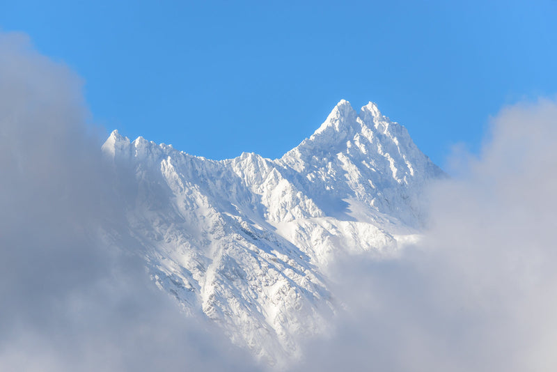 Parting clouds reveal the Remarkables covered in fresh snow in the morning light, Queenstown.