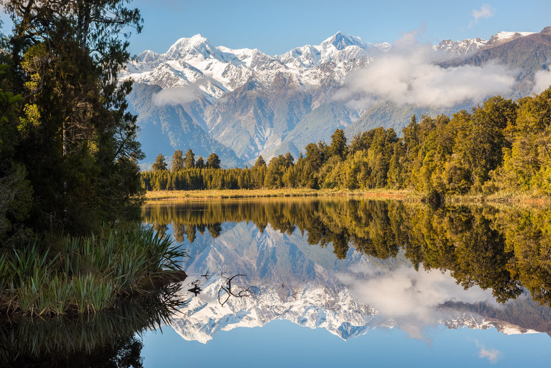 A calm start to the morning looking towards the Southern Alps from the shore of Lake Matheson.  Aoraki Mt Cook and Mt Tasman are New Zealand's two tallest mountains.