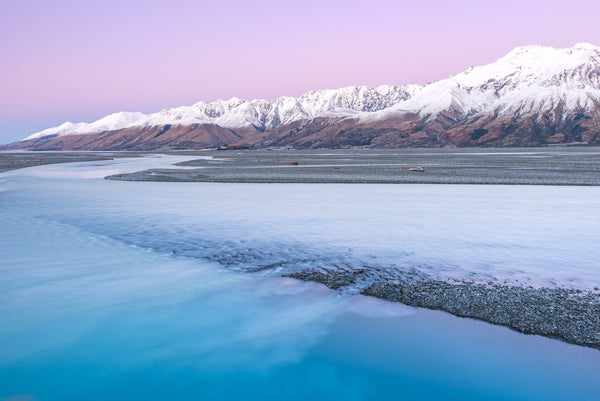 On a clear cold winters morning, the dawn hues complement the waters of the Tasman River, looking across the Delta, as water flows out into Lake Pukaki