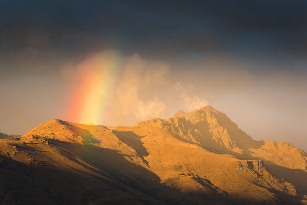 A rail squall passes over Cecil Peak creating a beautiful rainbow in the afternoon light, Queenstown.