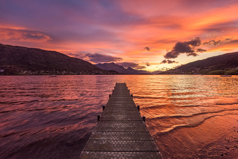 A gorgeous pink sunset lights up the skies over Frankton Arm, Lake Wakatipu as seen from Frankton Beach near Queenstown